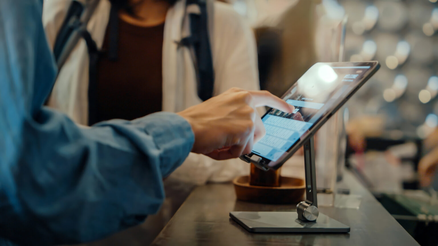 Gast nutzt ein digitales Self-Check-in-Terminal an der Hotelrezeption